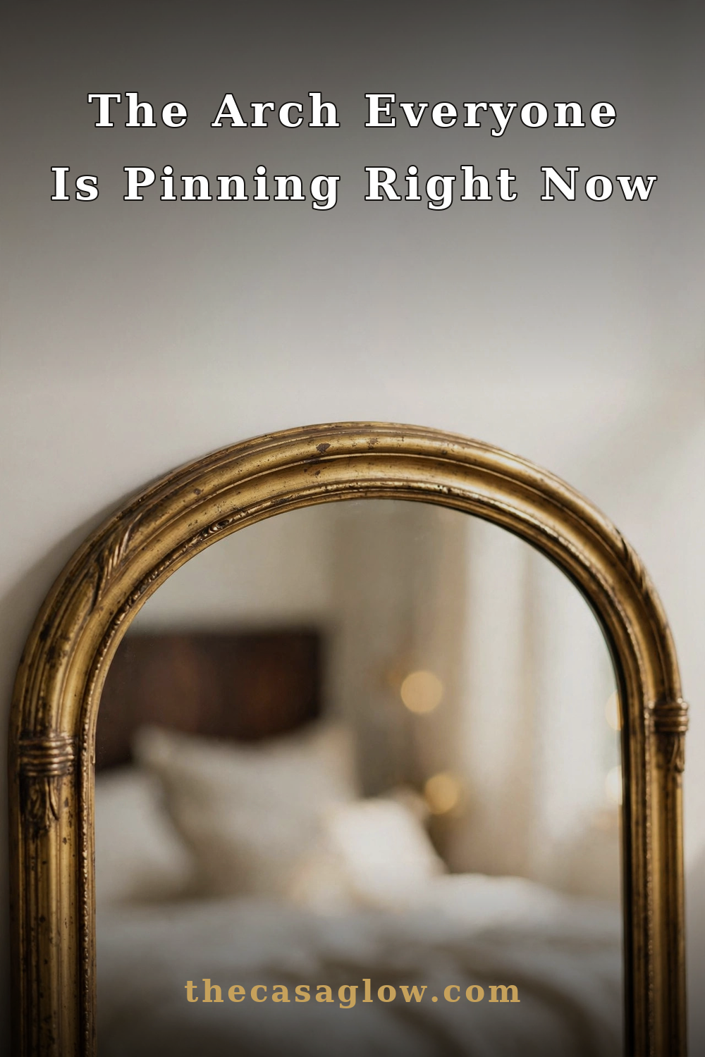 Gold arched floor mirror styled in a serene ivory bedroom