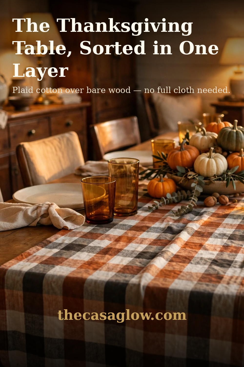 The Thanksgiving table, sorted in one layer — DII plaid runner over bare wood with a pumpkin centerpiece