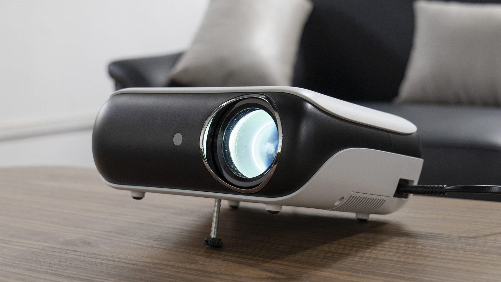 HAPPRUN Native 1080P Bluetooth Mini Projector (H1) on a wooden table, lens glowing