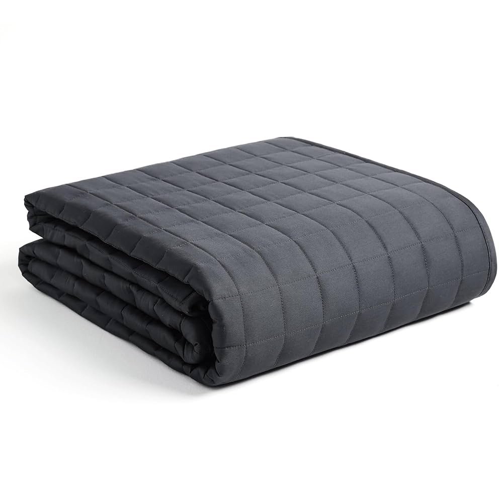 YnM Exclusive Weighted Blanket 15lbs, dark grey, draped on a cozy bed